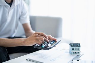 Foto: Mann tippt auf Taschenrechner